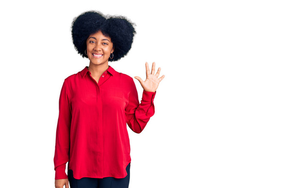 Молода афроамериканка, одягнена в повсякденний одяг, показує і вказує вгору пальцями номер п'ять, посміхаючись впевнено і щасливо.  - Фото, зображення