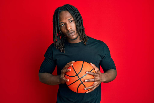 アフリカ系アメリカ人の男性は、バスケットボールボールを懐疑的で緊張しており、問題のために動揺していることを眉をひそめています。否定的な人.  - 写真・画像