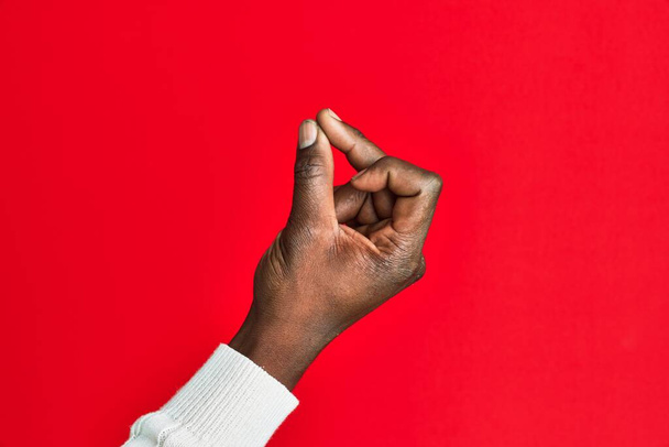 Braço e mão do jovem negro afro-americano sobre fundo isolado vermelho estalando os dedos para o sucesso, gesto símbolo fácil e clique com a mão  - Foto, Imagem