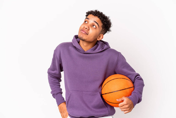 Jovem afro-americano encaracolado homem isolado jogando basquete sonhando em alcançar objetivos e propósitos - Foto, Imagem