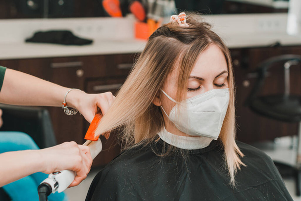 Haarverzorging, kapper knipt de uiteinden van het haar en straalt de lengte, het werk van kappers tijdens de wereldwijde coronavirus pandemie.nieuw - Foto, afbeelding