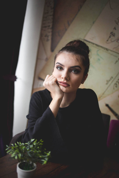 A shallow focus of a Caucasian brunette female wearing a black shirt in a cafe - Fotoğraf, Görsel