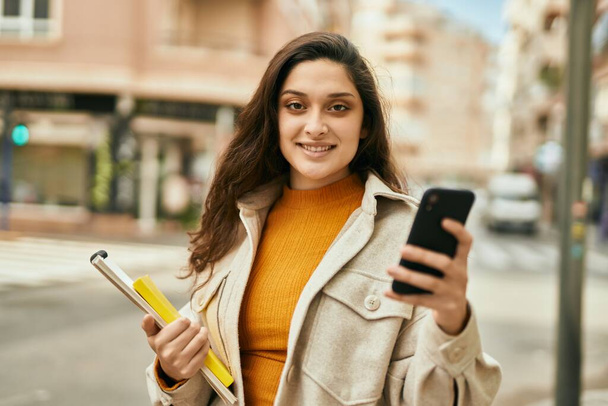Jeune femme du Moyen-Orient souriant heureux en utilisant un smartphone à la ville. - Photo, image