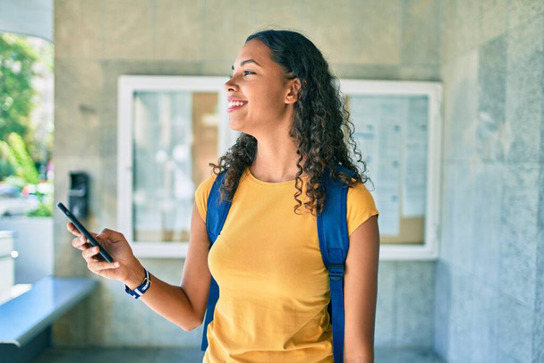 Νεαρή Αφροαμερικανή φοιτήτρια που χρησιμοποιεί smartphone στο πανεπιστήμιο. - Φωτογραφία, εικόνα