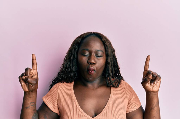 Africká mladá žena ukazuje prsty dělat rybí obličej s ústy a přimhouřenýma očima, bláznivé a komické.  - Fotografie, Obrázek