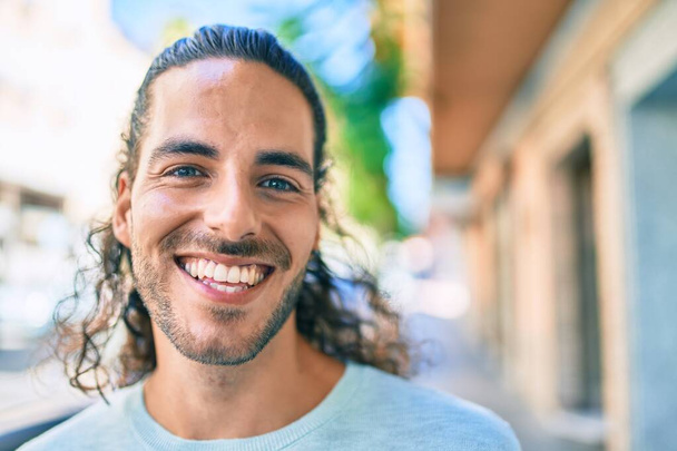 Joven hombre hispano sonriendo feliz mirando a la cámara en la ciudad. - Foto, imagen