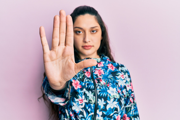 Beautiful middle eastern woman wearing casual floral jacket doing stop sing with palm of the hand. warning expression with negative and serious gesture on the face.  - Photo, Image