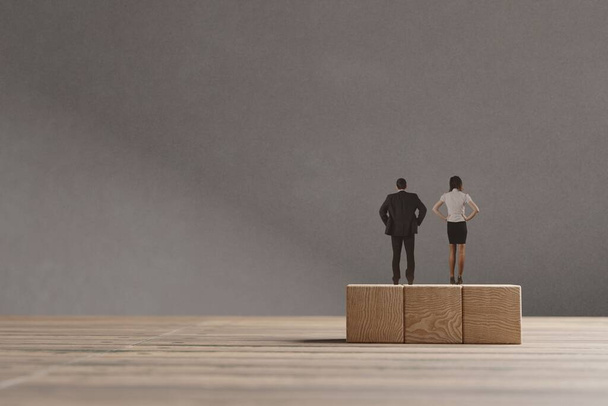 Миниатюрные мужчина и женщина стоят на деревянных блоках. Концепция равных возможностей для полов. - Фото, изображение