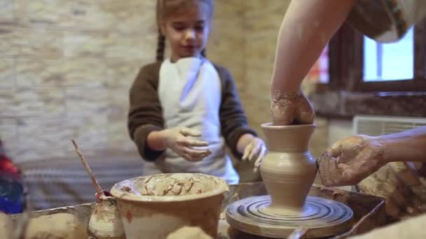 Chica jugando con el modelado de arcilla en la rueda de cerámica en el taller, arte artesanal, hobby artesanal y ocio - Imágenes, Vídeo