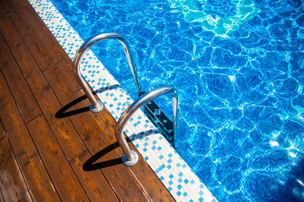 Chwyć drewnianą drabinę w basenie z błękitną wodą, światło słoneczne - Zdjęcie, obraz