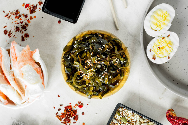 házi főzés hínár saláta, rák, tojás, szezám és tökmag. Veganizmus az ételben. egyszerű ázsiai receptek otthon. alga mosogatás.szelektív fókusz - Fotó, kép