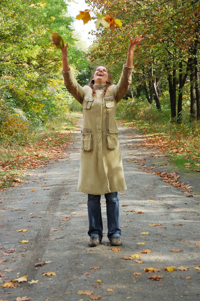 Happy young woman tosses up yellow leaves - Φωτογραφία, εικόνα