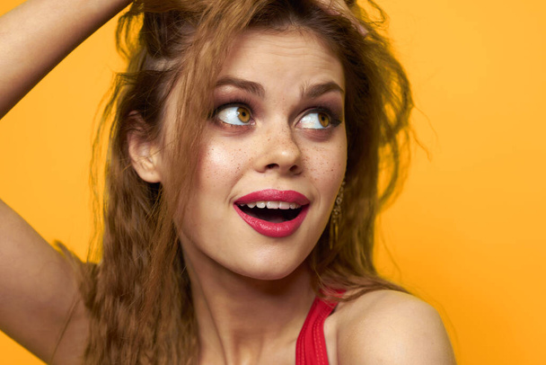 Kaunis nainen aaltoileva hiukset punainen säiliö top muoti elämäntapa kosmetiikka keltainen tausta - Valokuva, kuva