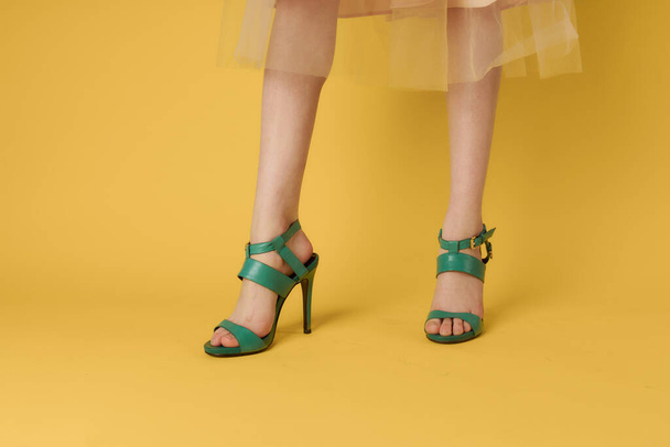 Female legs green shoes elegant lifestyle yellow background - Fotoğraf, Görsel