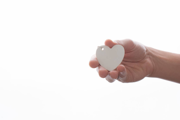 Білий об'єкт у формі серця в руці на білому тлі
 - Фото, зображення