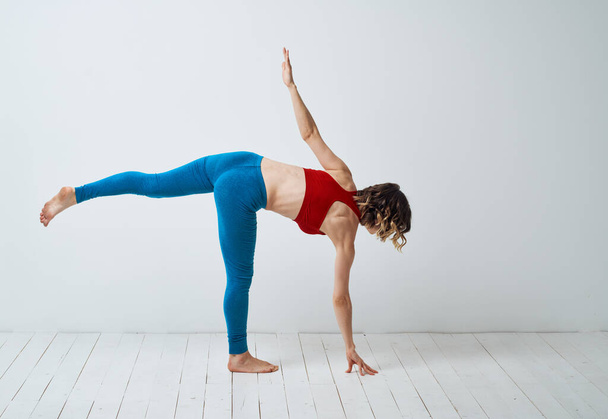 équilibre femme se tient sur une jambe Dans une pièce lumineuse et leggings Yoga asana - Photo, image