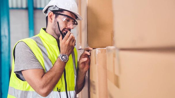 Professional cargo worker talks on portable radio to contact another worker - 写真・画像