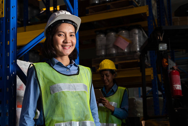 Portrait de jeune femme asiatique ouvrière d'entrepôt souriant dans l'entrepôt - Photo, image