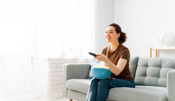 Young woman watching  TV, movies with popcorn. Girl spending time at home. - Photo, image