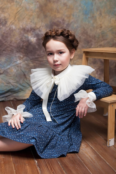 Portré egy kislányról, aki kék ruhában pózol egy felborzolt gallérral a késő reneszánszból.. - Fotó, kép