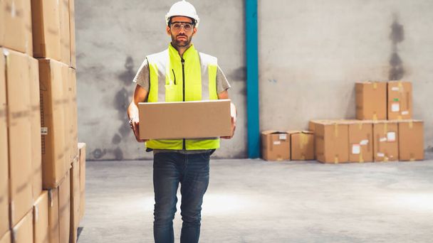 Warehouse worker carrying cardboard box in the warehouse - Photo, Image