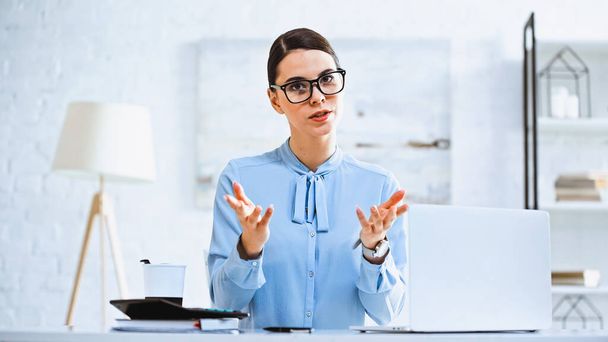 serious businesswoman looking at camera and pointing with hands in office - Photo, Image