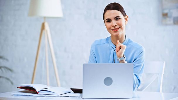 smiling businesswoman sitting at workplace near laptop - Photo, Image