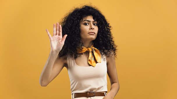 Молода іспаномовна жінка показує стоп жест ізольовано на жовтому
 - Фото, зображення