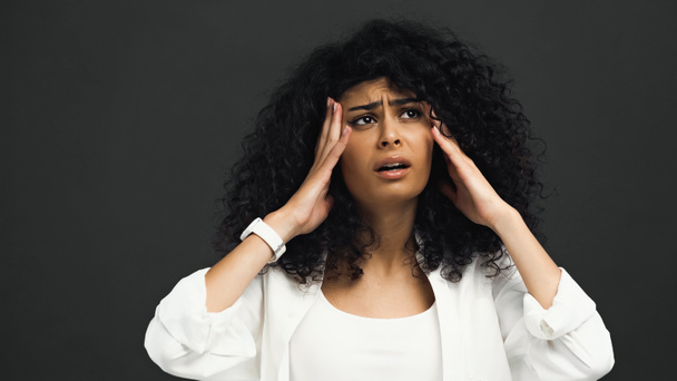 Stressed hispanic woman with hands near head isolated on black  - Photo, Image