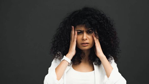 latino vrouw die lijden aan hoofdpijn geïsoleerd op zwart  - Foto, afbeelding