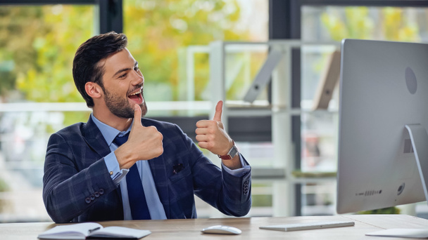 boldog üzletember mutatja hüvelykujját fel, és miután videohívás az irodában  - Fotó, kép