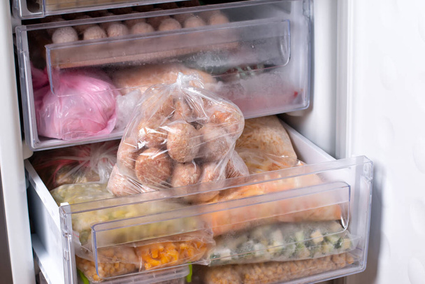 Productos semielaborados, albóndigas congeladas, empanadas de carne en bolsa de plástico en nevera, horizontales - Foto, Imagen