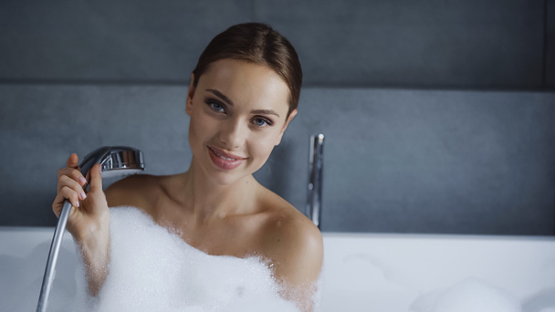 szczęśliwa młoda kobieta bierze kąpiel z pianką w białej wannie  - Zdjęcie, obraz