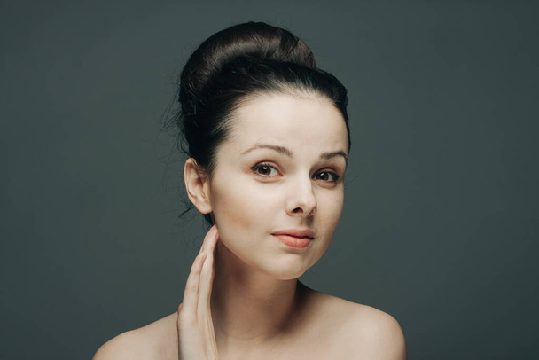 brunette with bare shoulders gathered hair hand near face - Фото, зображення