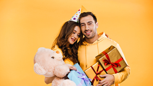 namorado feliz e namorada com presentes abraçando isolado no amarelo - Foto, Imagem