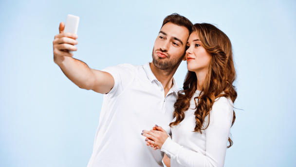 sorrindo casal tomando selfie isolado em azul - Foto, Imagem
