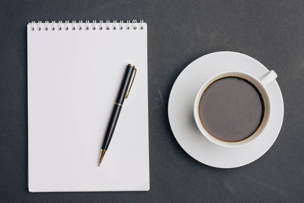 the dark background a Cup of coffee office Notepad handle the view from the top - Photo, Image
