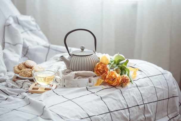 Tea, cookies and a bouquet of fresh tulips in bed. Breakfast and spring morning concept. - Photo, Image