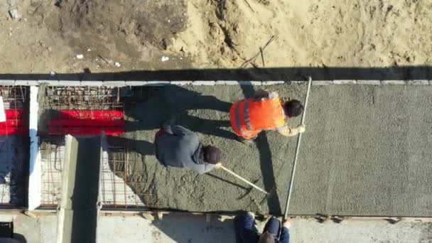Над видом, накладные расходы на строителей распространяются и выравнивание свежего бетона в квадратной траншеи после заливки из смесителя грузовик на незавершенном мосту. - Кадры, видео