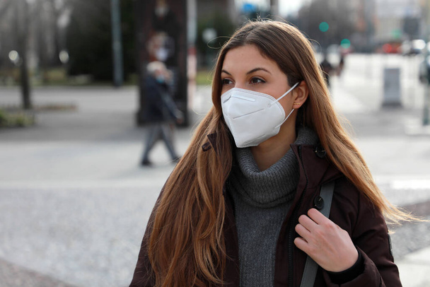 Portrait de jeune femme portant FFP2 KN95 masque facial en vêtements d'hiver à l'extérieur - Photo, image