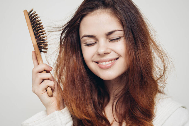mulher feliz com escova de cabelo no fundo claro e cabelo saudável - Foto, Imagem