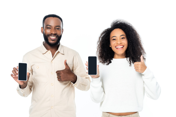 joyeux couple afro-américain montrant pouces levés tout en tenant les téléphones cellulaires avec écran vide isolé sur blanc - Photo, image