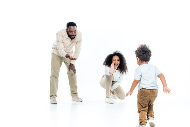 emocionado africano americano mujer dando alta cinco a niño pequeño hijo caminando en blanco  - Foto, Imagen