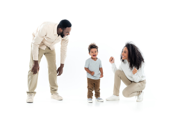 excited african american woman showing win gesture near amazed son and happy husband on white - Photo, Image
