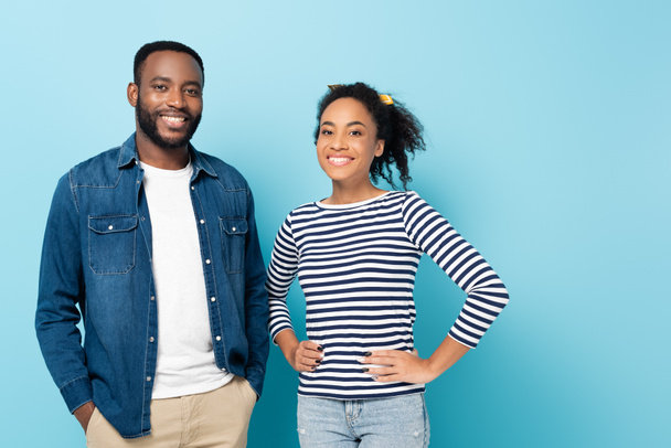 alegre casal afro-americano sorrindo para a câmera enquanto em pé no azul - Foto, Imagem