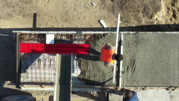 上の図では、建設労働者のオーバーヘッドは、彼はミキサー車から注ぐ後、新鮮なコンクリートの過剰を取るためにシャベルを使用しているとして. - 映像、動画