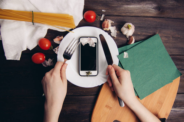 telefon egy tányérban szeletelés egy késsel eszik fa asztal - Fotó, kép