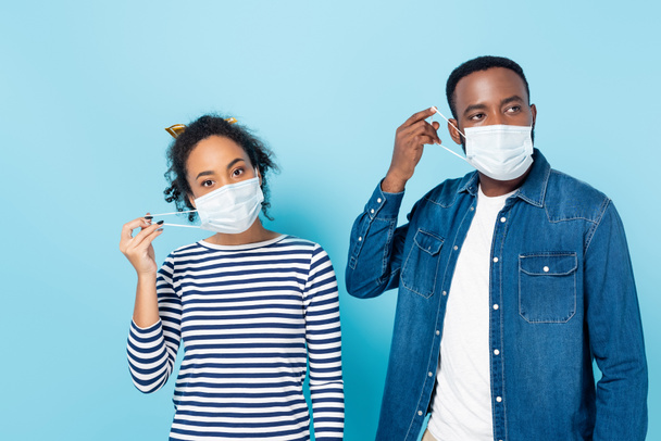 jeune couple afro-américain portant des masques médicaux sur bleu - Photo, image