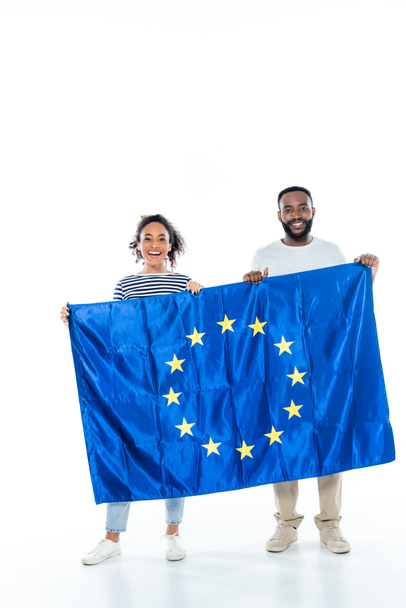 Genç Afrikalı Amerikalı çift Avrupa Birliği bayrağını beyazların üzerinde tutarken kameraya gülümsüyor - Fotoğraf, Görsel