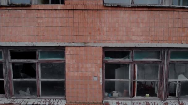 Разбитая рама и разбитое стекло большого окна, красная кирпичная стена - Кадры, видео